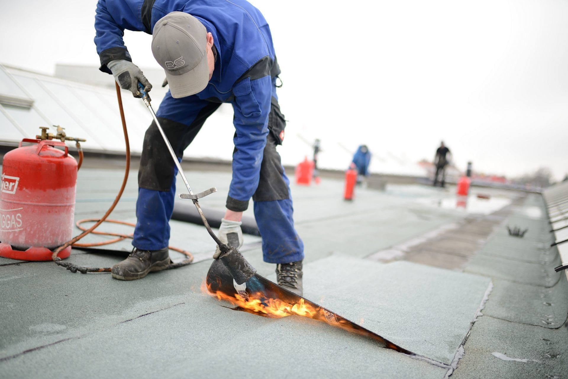 Dachsanierung | Flachdach Reparatur: Dachdecker verschweißen Dachbahn (© Sven Böttcher / stock.adobe.com)