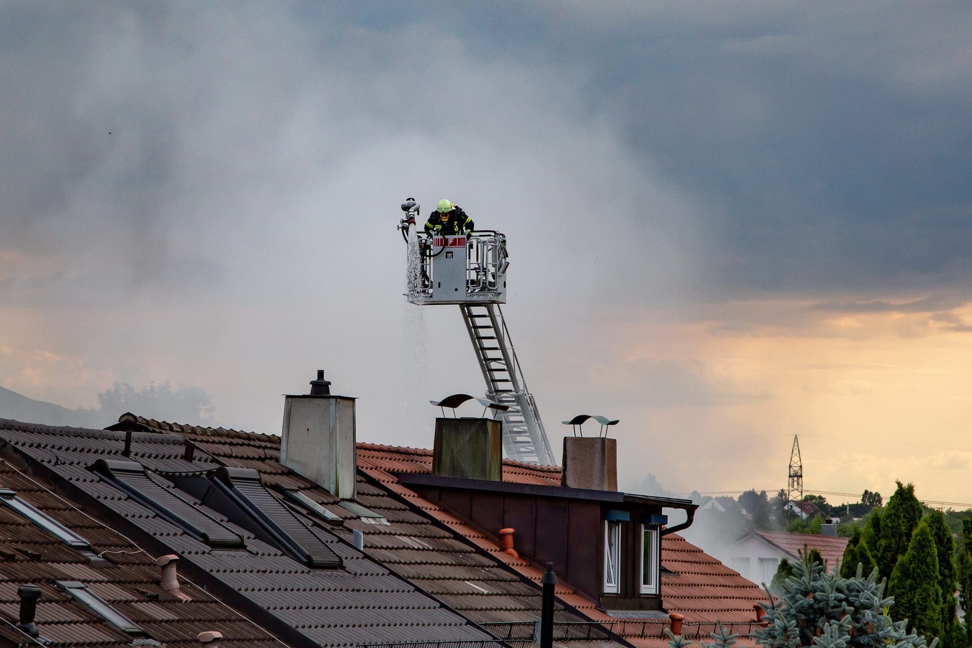 Feuerwehrmann inspiziert Dach und Schornstein von einer Drehleiter aus (© smartmediadesign / stock.adobe.com)