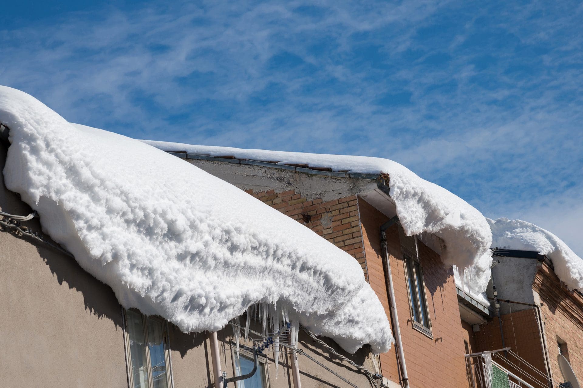 Schneelast, Schneedruck, Schneemassen: Nicht nur die Gefahr durch Eiszapfen und Dachlawinen ist ein Haftungs-Problem für Gebäude-Besitzer. Wenn Schneeverwehungen / Flugschnee bei starkem Schneefall unter den Dachziegeln hindurch weht, gibt es bei späterem Tauwetter häufig Wasserschäden im/am Dachstuhl. (© AP / stock.adobe.com)