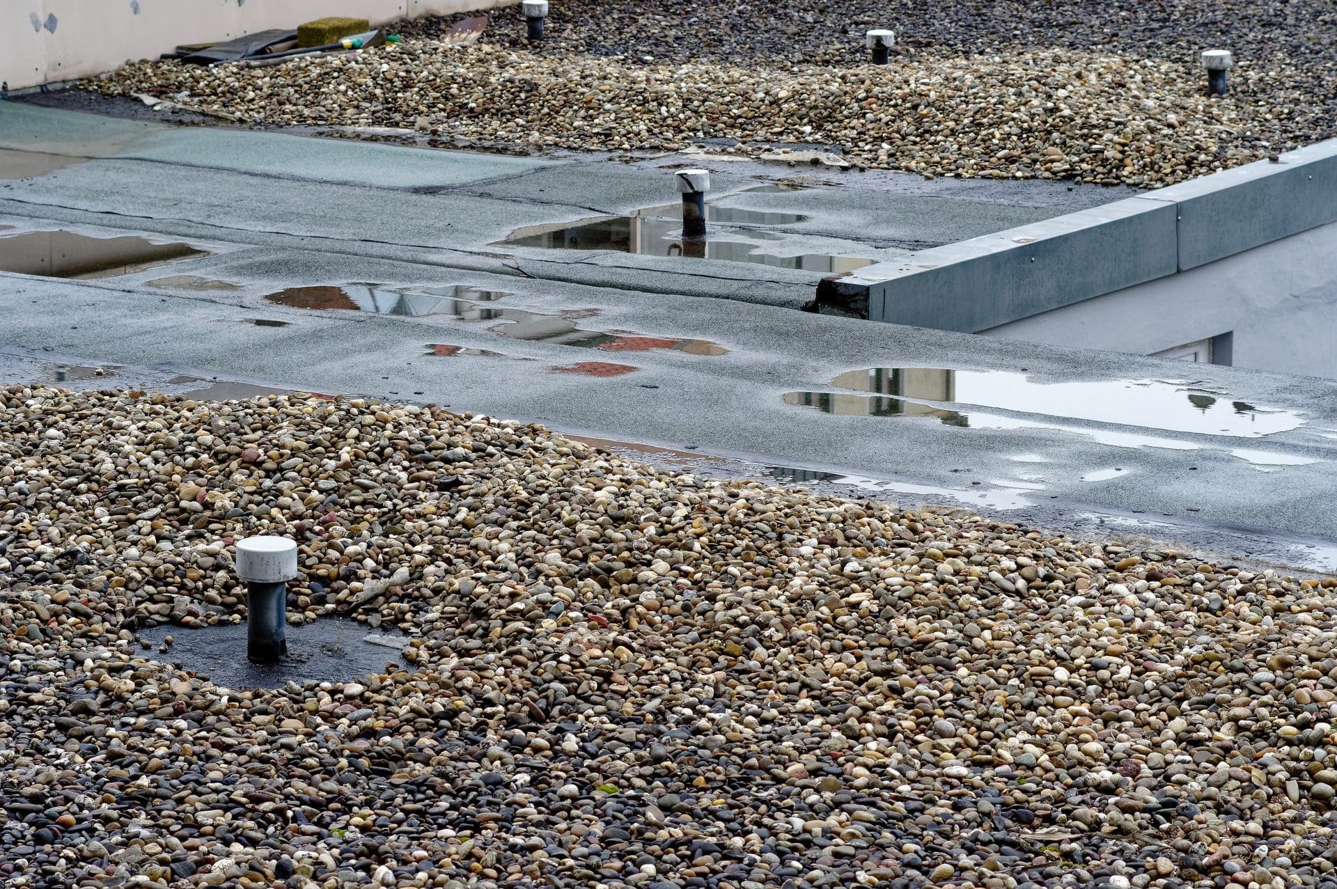 Regenwasser steht auf dem Flachdach - ist dieses undicht, stellt sich schnell die Frage nach Handwerkern / Dachdeckern für die Reparatur, und es entstehen Unsicherheiten bzgl. der Kostenübernahme. Wer muss was zahlen? Übernimmt z.B. die Gebäudeversicherung die Schäden für ein undichtes Flachdach? Für die Reparatur an sich? Für die Folgeschäden / Wasserschäden durch die Undichtigkeit?!... (© DatenschutzStockfoto / stock.adobe.com)