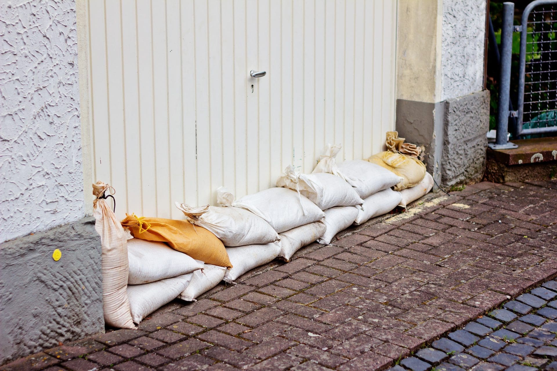 Schadenminderungspflicht: Schadenminderung / Schadenvorbeugung: Hier wurde das Garagentor mit Sandsäcken gegen Hochwasser so gut es geht abgedichtet (© TIMDAVIDCOLLECTION / stock.adobe.com)